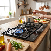 Midea 90cm gas-on-glass hob in use with a pot boiling on the triple-crown burner and tomato sauce simmering