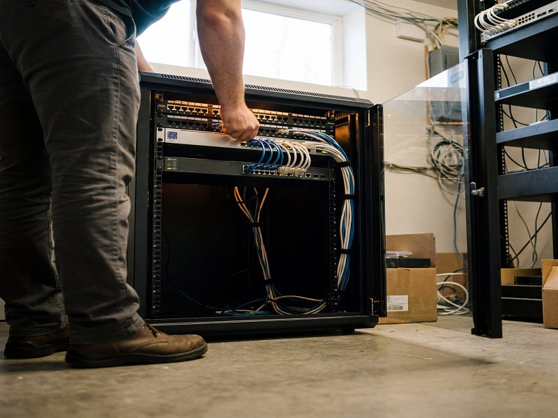 Low-angle view of a technician wiring equipment inside an open Zatech server cabinet