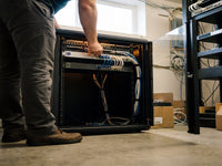 Low-angle view of a technician wiring equipment inside an open Zatech server cabinet